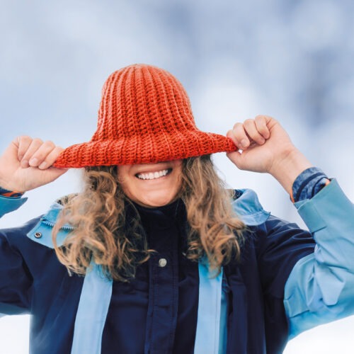 freundliche Frau versteckt unter rotem Hut im Schnee